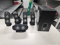 Full set of four satellite speakers, center channel speaker, and subwoofer shown on table