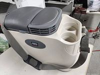 Side view of the beige Vector travel cooler with black lid and cup holders, showing the carrying strap.