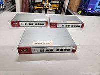 Three ZyXEL Unified Security Gateway devices on a table, front view showing ports and labels.