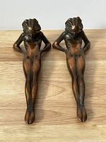 Top view of two bronze female figure bookends side by side showing front detail and patina.