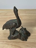 Front view of bronze pelican sculpture showing bird's body, beak, and base
