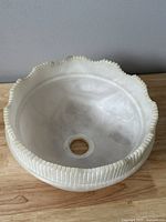 White marble circular mini sink showing the scalloped decorative edge and polished interior surface.