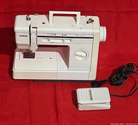 Front view of the white Brother VX-800 Series sewing machine with stitch selection markings and attached foot pedal.