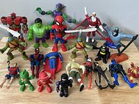 25 assorted mini action figure toys including Marvel superheroes, Teenage Mutant Ninja Turtles, and PJ Masks characters, displayed on a table.