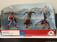 Front view of six figurines in original plastic and cardboard packaging showing full set including three Spider-Man figures, The Vulture, and Iron Man.