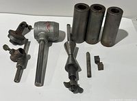 Full set showing all components including the main tool with logo, three cylindrical sleeves, tapered adjusting tool, and two small metal parts.