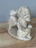 Front angle view of the hand-carved vintage stone figurine showing seated figure with bird on back, carved with detailed facial features and patterns.