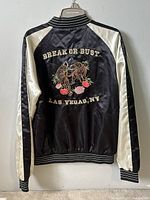 Back view of Forever 21 men's souvenir bomber jacket featuring embroidery 'Break or Bust', tiger design, and 'Las Vegas, NV' text. Satin black body with cream satin sleeves and ribbed black/white striped cuffs, collar and waistband.