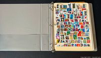 Open album showing a densely filled page of colorful vintage stamps on a cream-colored page in a ring binder album.