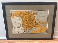 Full view of the framed Animated Map of New Brunswick artwork by Arthur Edward Elias, showing the black frame and beige mat around the colorful illustrated map.