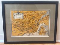 Full view of the framed animated map of Quebec showing the black wood frame, beige mat, and colorful illustrated map detail within glass.