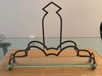 Front view of metal frame with Art Deco design on glass base, showing overall shape and design details.