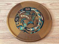 Full view of round cedar tray showing hand painted traditional Indigenous killer whale design on wood surface