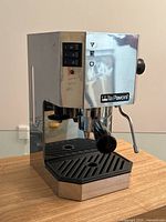 Front angled view of stainless steel espresso machine with black drip tray, portafilter, and control switches showing La Pavoni logo.