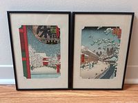 Both framed prints side by side against light wall showing overall appearance and scale