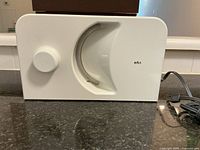 Side view of vintage Braun electric meat slicer showcasing white plastic body and thickness control dial.
