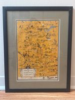 Full image of framed Animated Map of Alberta print by Arthur Edward Elias, showing the entire framed artwork on a floor against a wall.