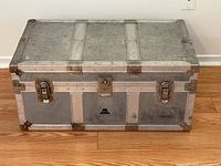 Front view of aluminum steamer trunk showing two latch closures and center lock