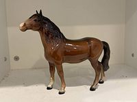 Frontal view of Beswick porcelain horse figurine showing shape, color, and repaired leg area.
