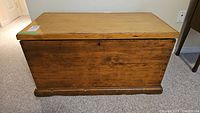 Front view of wooden blanket box showing natural wood grain and lock on lid.