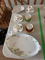 Overview photo showing the five demitasse cups with saucers arranged neatly in pairs and the unmarked floral platter with a small trinket tray on the side (not included in lot).