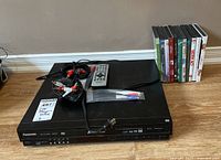 Panasonic DVD/CD player with remote control, cables, and eleven DVDs displayed upright behind the player.