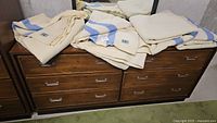 Four cream and blue striped wool blankets folded on a wooden dresser in basement setting.