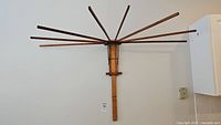 Full view of the wall mounted clothing dryer showing radiating wooden rods and vertical wooden mount.