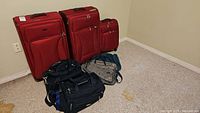 Three red upright luggage pieces of varying sizes and four carry bags on carpeted floor.