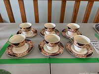 Six Myott Corona demitasse cups and saucers arranged on a table, showing overall set condition.