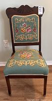 Full view of the wood chair with needlepoint cushions and carved top backrest.