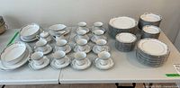 Full view of the 12-piece Noritake china set arranged on table, showing the various plates, bowls, cups, saucers, serving bowls, and platters included.