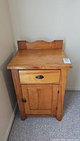 Front view of pine dry sink showing drawer with metal pull and cabinet door with metal clasp.