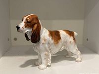 Side view of a Royal Doulton dog figurine showing the dog with white and brown patches and detailed texture.