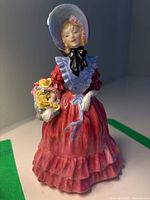Front view of Lady Betty figurine showing the pose, detailed facial features, and colorful dress with blue shawl and bonnet.