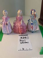 Overall view of the three Royal Doulton porcelain figurines posed together on a white surface.