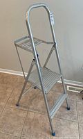 Front angle view of the two-step aluminum ladder showing metal steps, paint tray, and plastic foot caps