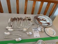 Layout of all items including spoons, spreaders, engraved plate, saucer, salt cellar and salt spoon