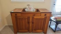 Front view of pine wash stand with washbasin and pitcher centered on top showing drawers and cabinet doors