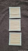 Three small bamboo place holders laid flat on a gray fabric surface, showing front side with bamboo slats and fabric edging.