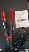 Two CHI ceramic hairstyling irons with red plates and digital controls, includes power cords and owner's manuals.