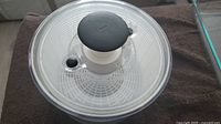 Top view of the OXO salad spinner showing the transparent bowl and black lid with spinning knob.