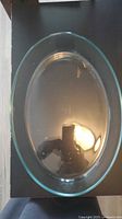 Top view of a transparent oval glass dish on a dark surface, showing clear glass and reflective light.
