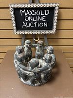 Front angle showing ceramic candle holder with seven people figures holding hands in a circle; chalkboard sign behind reading Maxsold Online Auction.