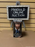 Full view of boxed Wacky Wobbler talking bobble-head of Willie from Duck Dynasty with a chalkboard in background.