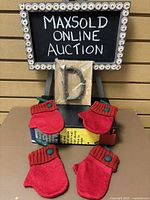 Lot display with matte black framed board reading 'Maxsold Online Auction', showing the packaged Letter D ornament and four red mitten ornaments.