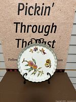 Front view of the quiche dish showing scalloped edge and fruit pattern of peaches and blackberries on cream porcelain.