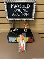 Overview photo showing the three items arranged on a box with a MaxSold Online Auction sign behind them.