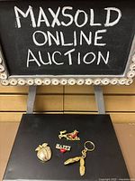 Lot overview showing three brooches and one keychain on black surface.