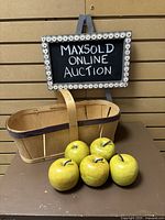 Front view of the slatwood basket with five yellow faux apples arranged in front, displaying basket shape and apple appearance.